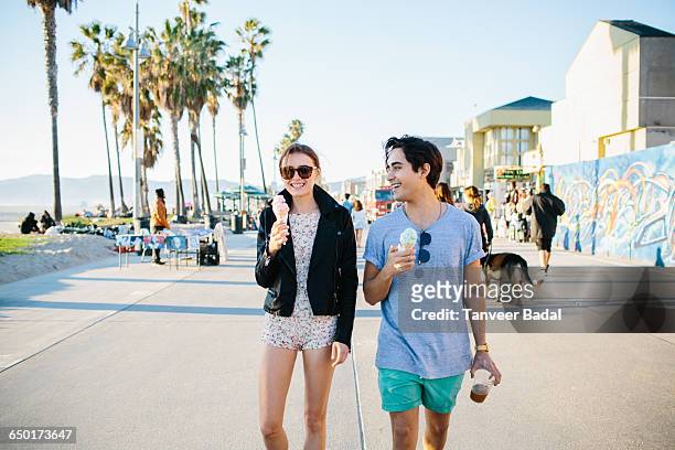 young couple strolling eating ice cream cones, venice beach, california, usa - los angeles photos et images de collection