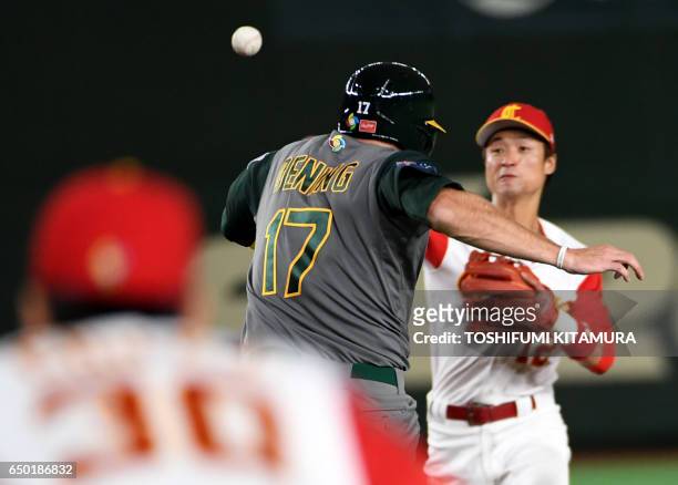 Mitch Dening of Australia runs towards the second base while China's second baseman Du Xiaolei throws the ball to first base to get a double during...