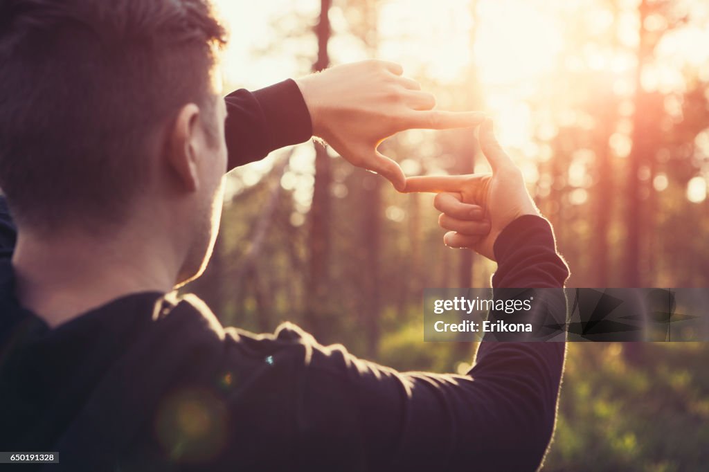 Human hands framing distant sun rays