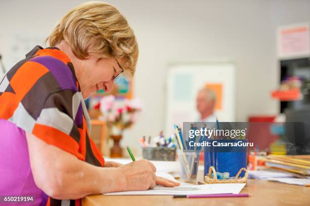 senior woman coloring at the community center - coloring stock pictures, royalty-free photos & images