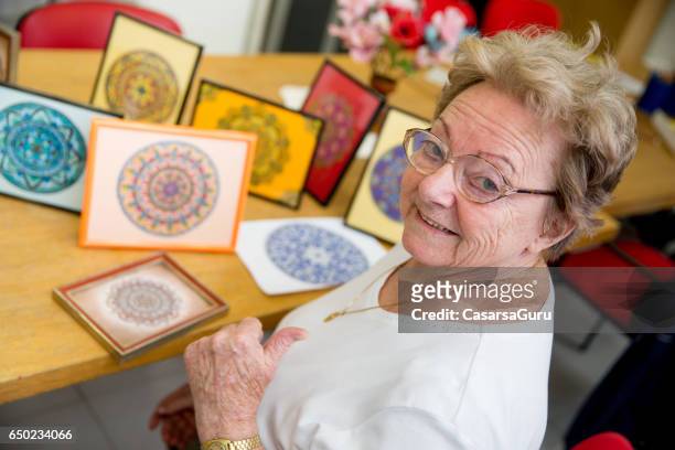 donna anziana attiva che mostra artigianato artistico fatto a mano nel community center - art and craft foto e immagini stock