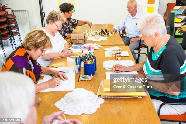 group of active seniors socializing at the activity center - community center interior stock pictures, royalty-free photos & images