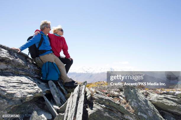 hiking couple pause on mountain summit, look off - new zealand travel stock pictures, royalty-free photos & images