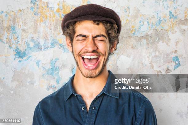 portrait of young man laughing, eyes closed - flat cap stock pictures, royalty-free photos & images