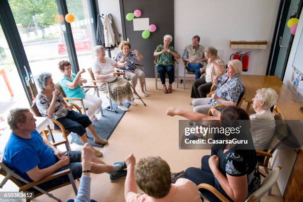 seniors doing relaxation exercises in the elderly day care center - active retirement community stock pictures, royalty-free photos & images