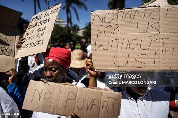 Street hawkers from the east-Pretoria township of Mamelodi hold cardboard signs during a demonstration in Pretoria on March 9, 2017 against a wave of...