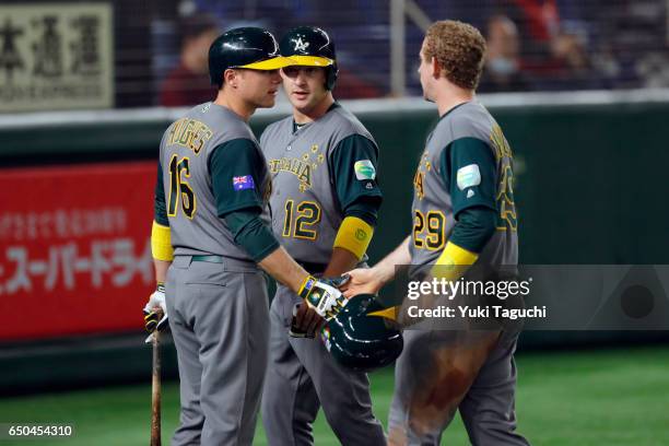 Brad Harman and David Kandilas of Team Australia are greeted by teammate Luke Hughes after they both scored a run during Game 4 of Pool B against...