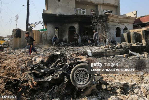 Iraqis through the rubble of destroyed homes and vehicles in the Shuhada neighbourhood of west Mosul, as Iraqi forces advance against Islamic State...