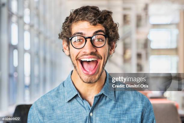 portrait of young man smiling, mouth wide open - hombre asombrado fotografías e imágenes de stock