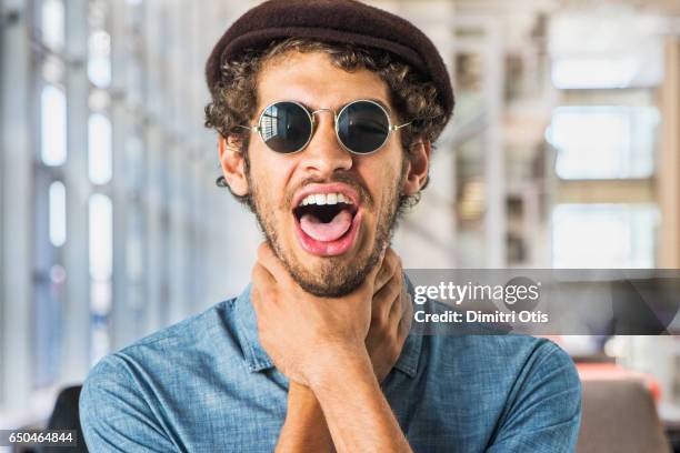 portrait of young man throttling himself - tongue stock pictures, royalty-free photos & images