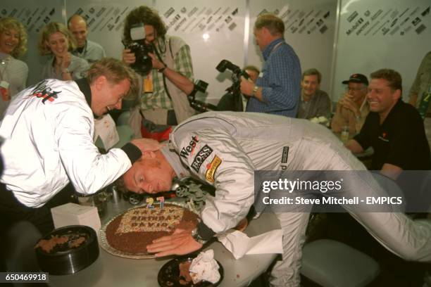 Mika Hakkinen tries to push birthday boy David Coulthard's head into his cake, which Mika presented to him on his 27th Birthday