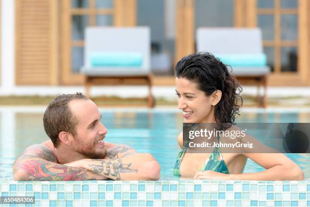 portrait of couple relaxing in swimming pool, talking - cool couple in apartment stock pictures, royalty-free photos & images