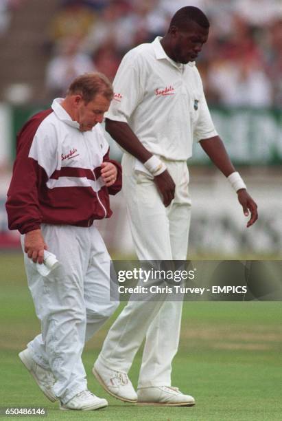 West Indies' Curtly Ambrose has to leave the field with physio Dennis Waite after injuring his groin