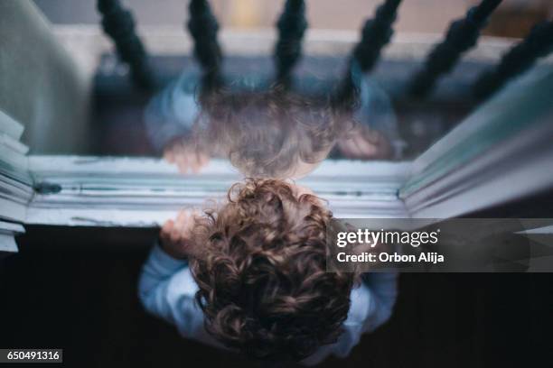 kid looking through the window - ausencia imagens e fotografias de stock