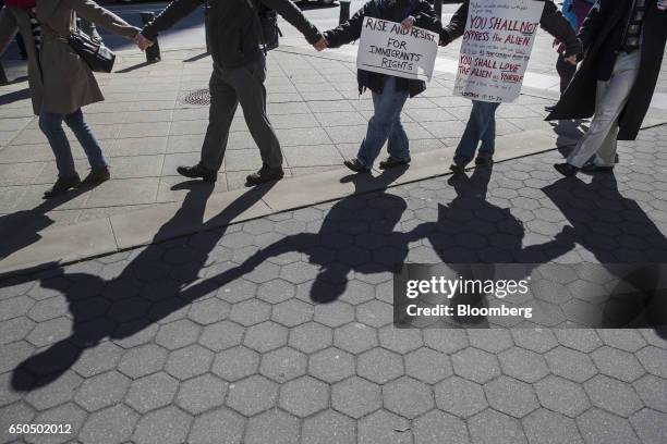 Demonstrators hold signs while marching to accompany immigration activist Ravi Ragbir, not pictured, to a check-in with Immigration and Customs...