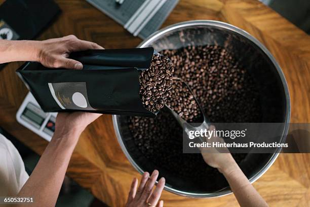 people working in roastery filling package - geroosterde koffieboon stockfoto's en -beelden