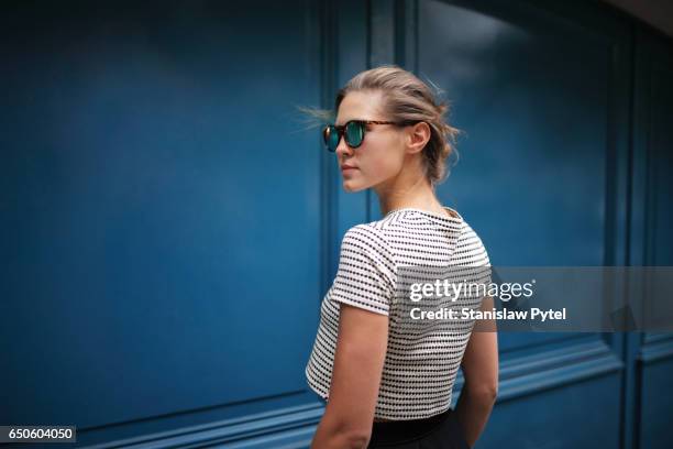 portrait of woman against blue wall - frau mit sonnenbrille stock-fotos und bilder