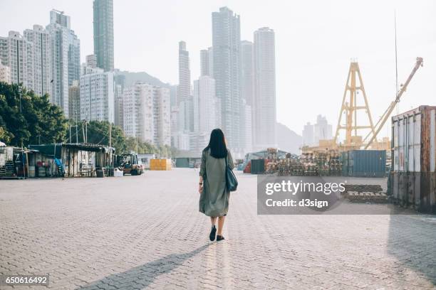 rear view of woman walking towards the city - woman full body behind stock-fotos und bilder