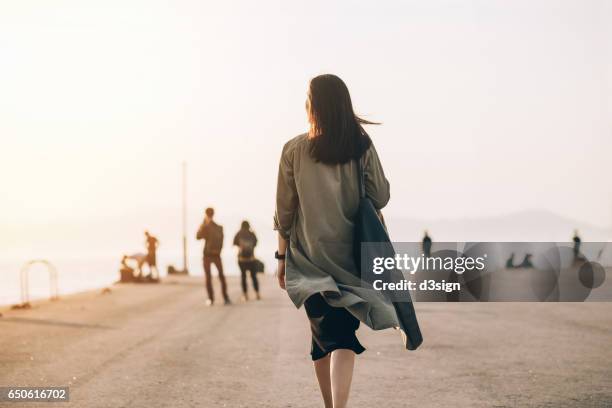 woman enjoying the stunning view of sunset by the harbour - back fotografías e imágenes de stock