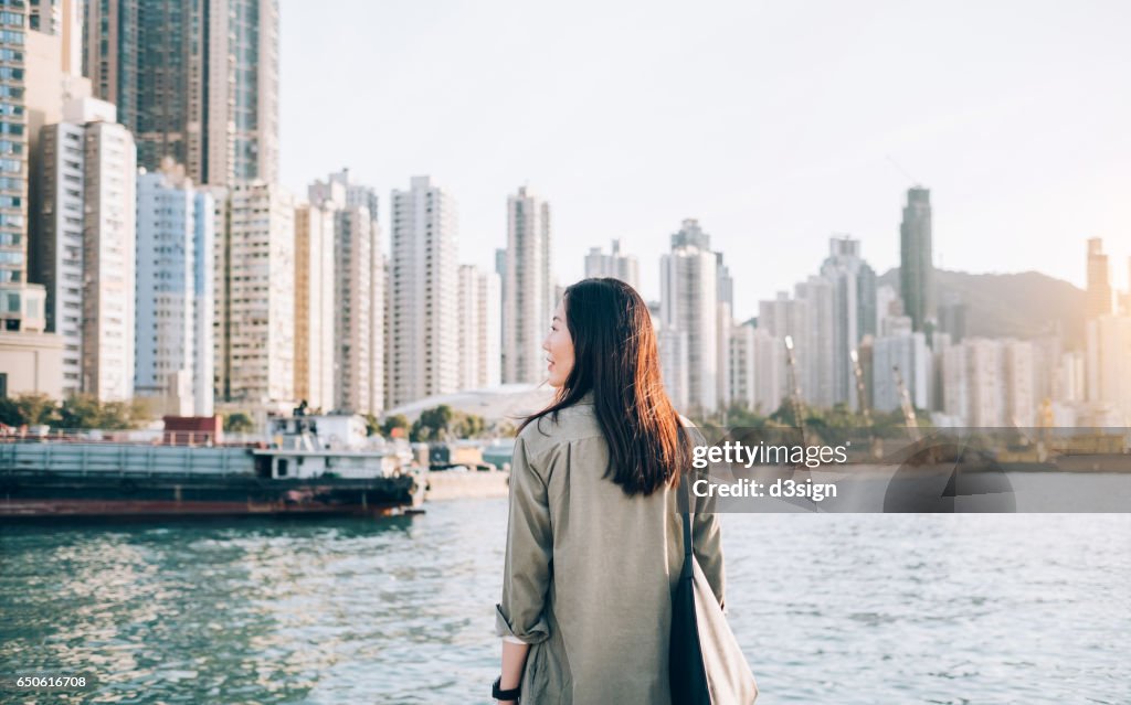 Pretty young girl enjoying the city view by the sea on a fresh morning