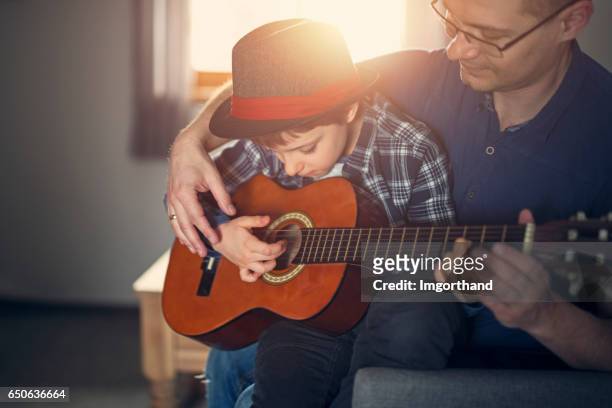 father teching son to play guitar - man fedora room stock pictures, royalty-free photos & images