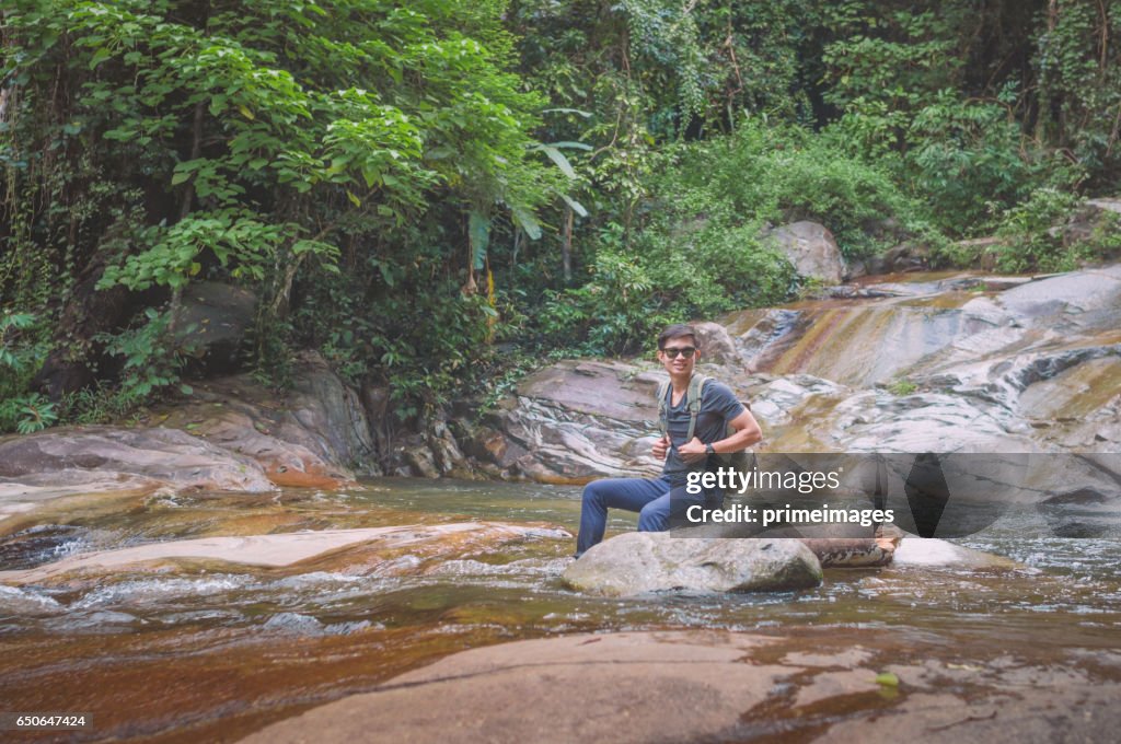 Hiker with backpack and laptop and phone at  waterfall  the forest.