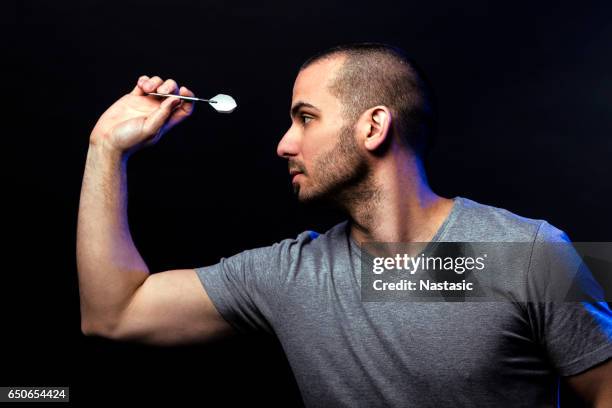 hombre disparando dardos - dart fotografías e imágenes de stock