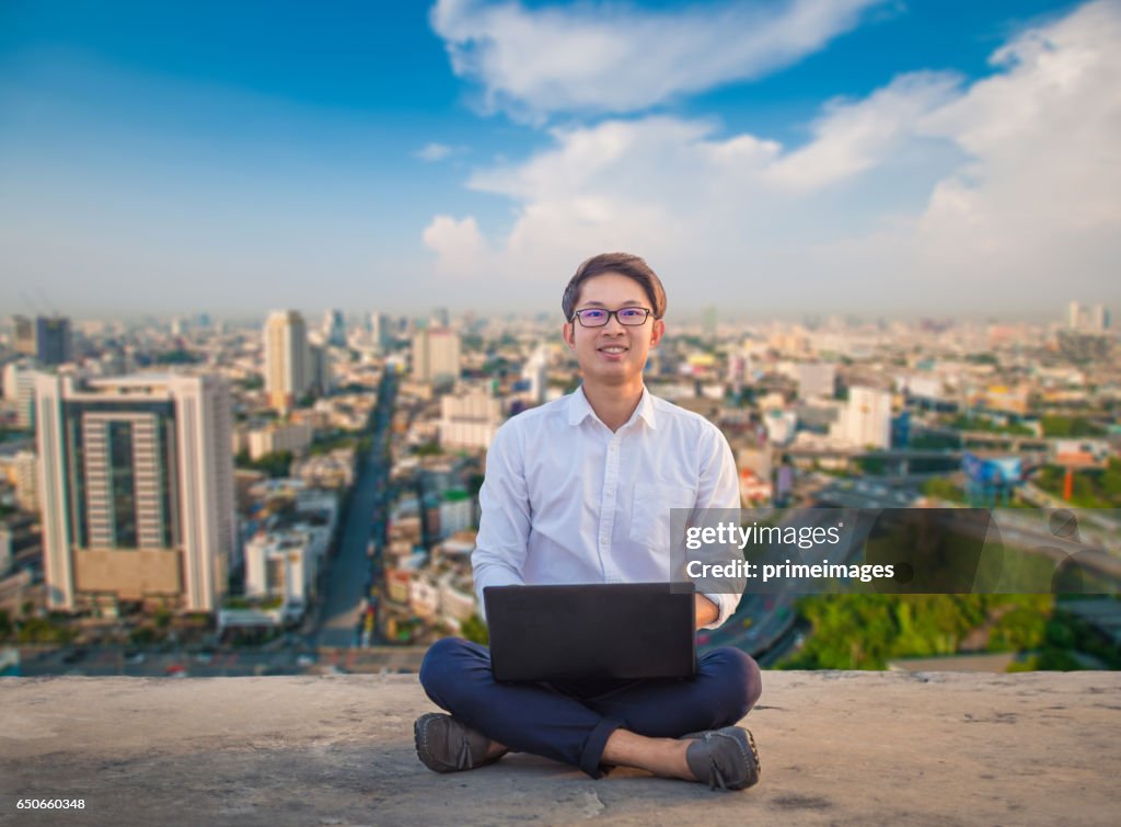 Giovane uomo d'affari che utilizza laptop e tablet digitale sfondo paesaggio urbano