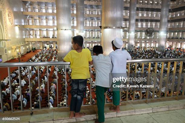 Three Muslim boys watch Friday Prayer ceremony from a balcony in Istiqlal Mosque on November 25, 2016 in Jakarta, Indonesia. Istiqlal Mosque is the...