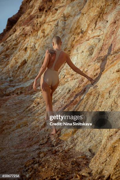 bold female in beige swimwear walking in yellow rocks, sunrise time - alien life stock pictures, royalty-free photos & images