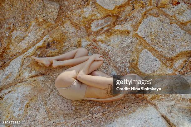 female laying down in fetal pose in rose quartz rocks - ko phangan stock pictures, royalty-free photos & images