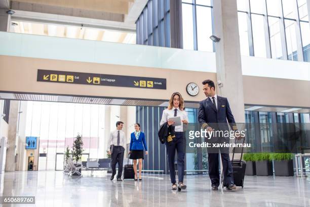 aircrew with luggage and tablet walking in airport - crew stock pictures, royalty-free photos & images