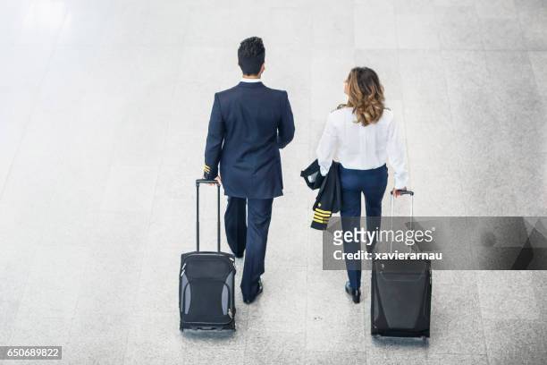 rear view of pilots walking on airport floor - female airport stock pictures, royalty-free photos & images