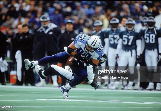 Frank Wycheck of the Tennessee Titans catches the ball as he is tackled by Brian Dawkins of the Philadelphia Eagles at the Veterans Stadium in...