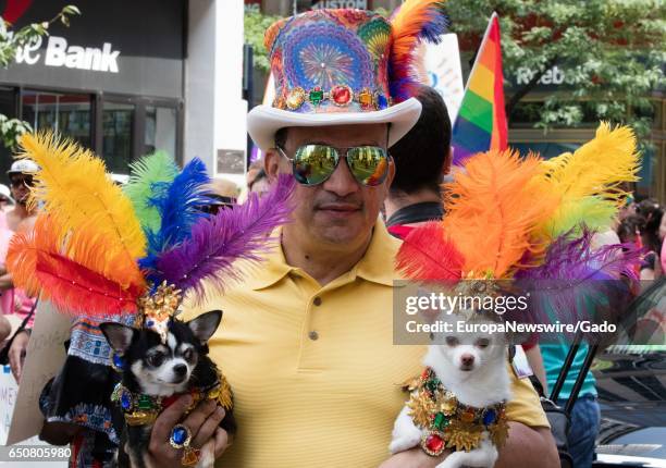 Man wears flamboyant, rainbow colored clothing and holds two small dogs during the 46th Lesbian, Gay, Bisexual and Transgender Pride March, New York...