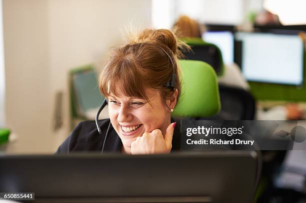 woman taking call  in call centre - call center headset stock-fotos und bilder