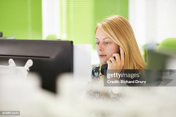 young woman taking call in office - telefonhörer stock-fotos und bilder