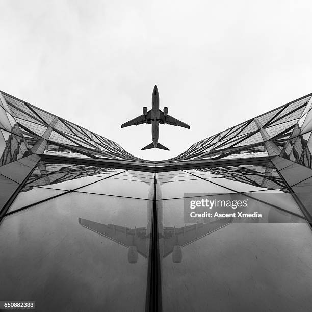 jet airplane passes overhead skyscrapers - aircraft skyscrapers stockfoto's en -beelden