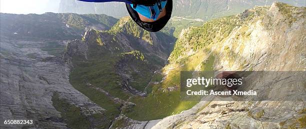 view up past face of wingsuit flier in mid flight - base jumping stock pictures, royalty-free photos & images