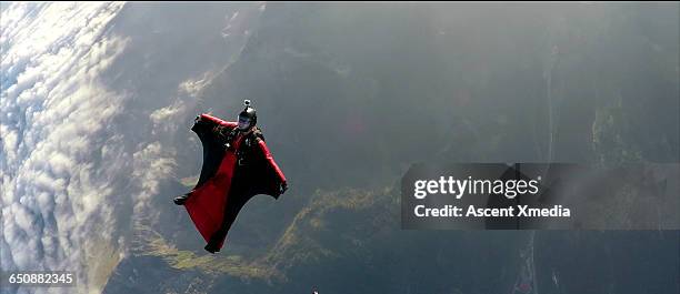 wingsuit flier faces backwards in mid air flight - wing suit stock pictures, royalty-free photos & images