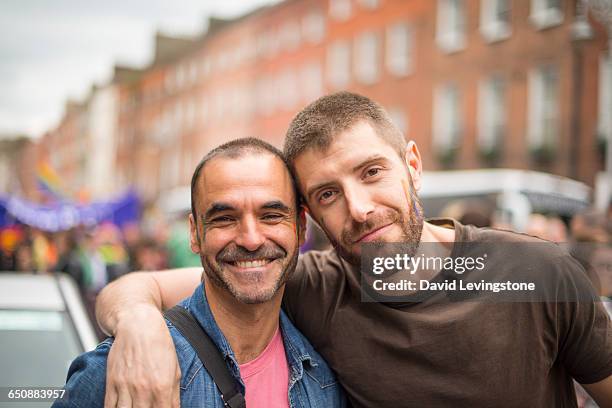 handsome gay couple during gay pride parade - hispanic gay man stock pictures, royalty-free photos & images