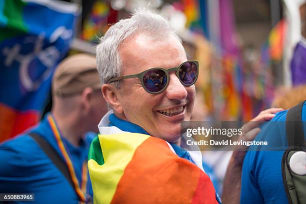 handsome man during gay pride parade - gay pride flag stock pictures, royalty-free photos & images