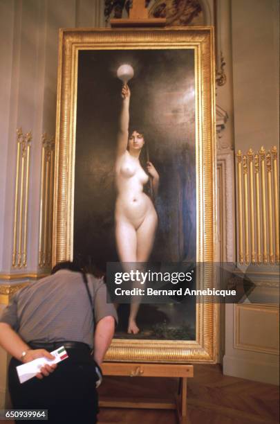 Man looks at a full-length painting of a nude woman at the Orsay museum.