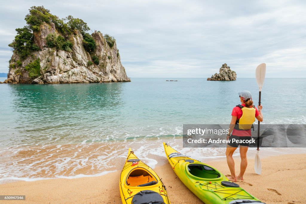 A woman is sea kayaking the coastline of Abel Tasman National Park