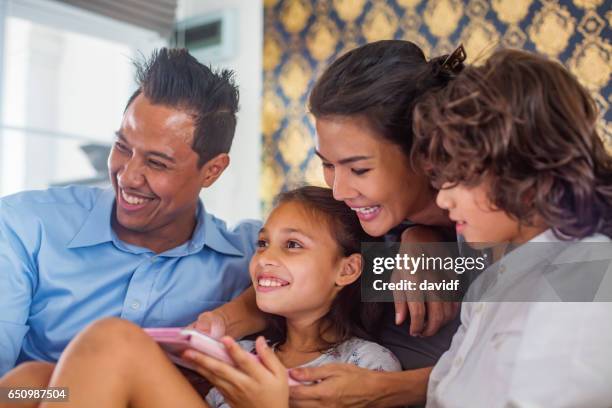 famiglia asiatica che gioca al tablet wiht mentre guarda la tv - popolo eurasiatico foto e immagini stock