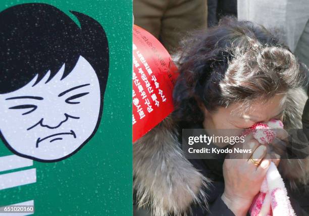 Woman cries with relief in Seoul on March 10, 2017 after South Korea's Constitutional Court ruled to uphold a parliamentary motion to impeach...