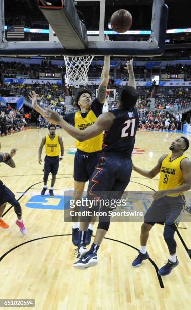 Michigan Wolverines forward D.J. Wilson scores against Illinois Fighting Illini guard Malcolm Hill in the second round of the Big 10 Tournament game...