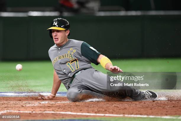 Outfielder Mitch Dening of Australia slides safely into the home plate to score a run by a RBI single of Infielder Logan Wade of Australia to make it...