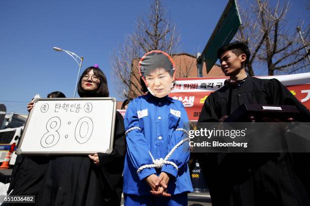 Demonstrator wearing a mask of former South Korea President Park Geun-hye stands, following the decision of the Constitutional Court of Korea to...
