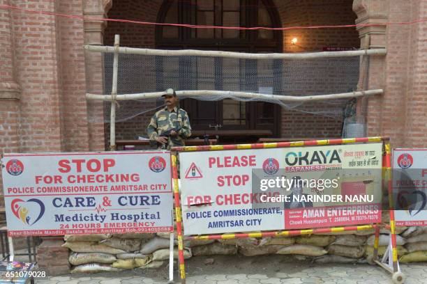 Indian soldiers stand guard outside a sealed 'strong room' where electronic voting machines are kept, on the eve of declaration of the 2017 assembly...